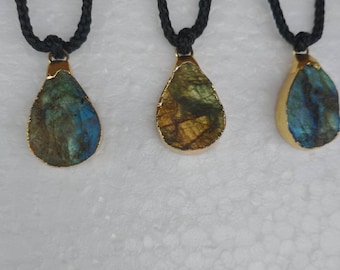 May include: Three gold-rimmed teardrop-shaped pendants with iridescent blue and green labradorite stones hanging from black cords.
