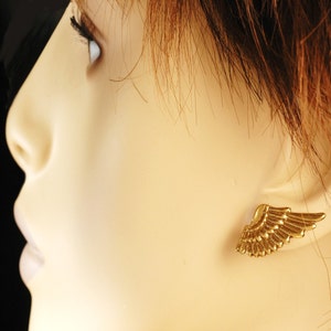 May include: A pair of gold-tone angel wing earrings. The wings are detailed and have a textured finish.