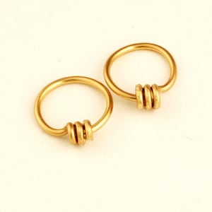 May include: Two gold hoop earrings with a stacked ring design. The rings are smooth and have a polished finish.