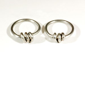 May include: Two silver hoop earrings with a twisted knot design.