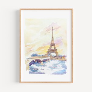 May include: Watercolor painting of the Eiffel Tower in Paris, France, with a bridge and river in the foreground. The artwork features soft pastel colors of yellow, pink, and blue, framed in a light wood frame.