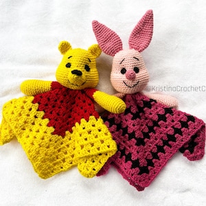 Op de afbeelding: Twee handgemaakte gehaakte babyknuffels. Eén is geel en rood, lijkt op een beer, en de andere is roze, lijkt op een konijn. Beide hebben een vierkant dekentje met een gestructureerd patroon. De tekst "KristinaCrochetCA" is zichtbaar.