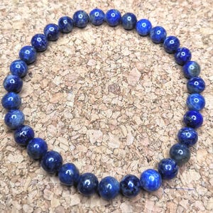 Op de afbeelding: Een blauwe edelsteen armband gemaakt met ronde kralen. De armband is gemaakt met donkerblauwe en lichtblauwe kralen.