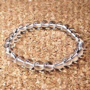 Könnte beinhalten: Ein Armband aus klarem Bergkristall mit runden Perlen. Das Armband besteht aus natürlichen Steinen und ist perfekt für den täglichen Gebrauch.
