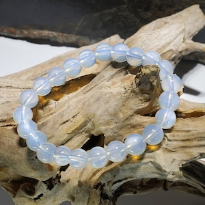 May include: A bracelet made of iridescent white opal beads. The bracelet is made of round beads and is strung on elastic.