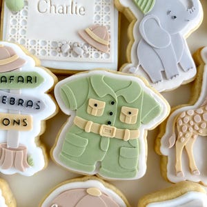 Op de afbeelding: Assortiment van versierde suikerkoekjes met een safarithema. Koekjes zijn onder meer een safari-outfit, een olifant met een feesthoed, een bord met "Safari", een verjaardagskoekje met de naam "Charlie" en een safarihoed.