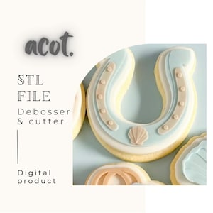 May include: A horseshoe-shaped biscuit decorated with light blue, beige, and white icing. The biscuit has a seashell design and small beige dots. The image also includes text that says "acot", "STL FILE", "Debosser & cutter", and "Digital product".