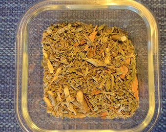 May include: A glass container filled with a blend of dried herbs and spices. The herbs are a mix of green and brown, with some pieces of wood visible.