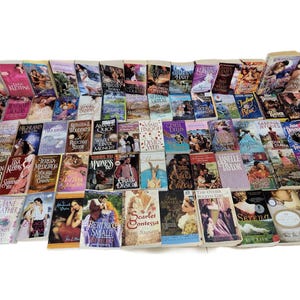 Peut inclure: Une collection de romans d'amour en format poche avec diff&eacute;rents titres et auteurs. Les livres sont dispos&eacute;s en rang&eacute;es et pr&eacute;sentent une vari&eacute;t&eacute; de couvertures avec des couleurs et des motifs diff&eacute;rents.