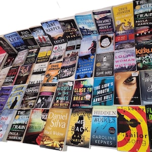 May include: A large collection of paperback books, mostly mystery and thriller novels, with various titles and authors. The books are stacked in a pyramid shape, with the titles facing outward.