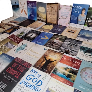May include: A large collection of books with various titles and authors, mostly focused on Christian faith and spirituality. The books are arranged in rows and columns, with some titles visible, such as "Seen Secure Free", "Proof of Heaven", "Why is God Laughing?", "You Gotta Keep Dancin", "Untangled", "I Declare", and "The Beauty of Broken".
