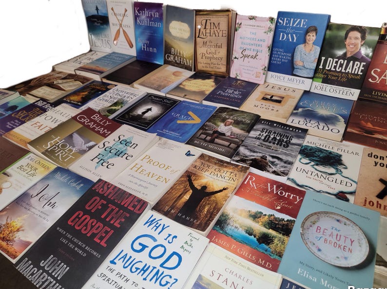 May include: A large collection of books with various titles and authors, mostly focused on Christian faith and spirituality. The books are arranged in rows and columns, with some titles visible, such as "Seen Secure Free", "Proof of Heaven", "Why is God Laughing?", "You Gotta Keep Dancin", "Untangled", "I Declare", and "The Beauty of Broken".