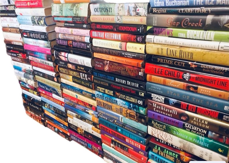 May include: A wall of books stacked vertically, with titles visible on the spines. The books are a mix of genres, including fiction, mystery, and thriller. Some of the titles include "Outpost!", "The Crimson Petal and the White", "Prime Cut", "Lee Child", "Midnight Line", "Star of the Sea", "The Red Horseman", "Salvation in Death", and "Stranger in Paradise".