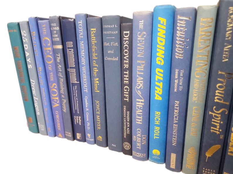 Pu&ograve; includere: Una collezione di libri con copertina rigida in varie tonalit&agrave; di blu e verde acqua, disposti su uno sfondo bianco. I titoli includono "Finding Ultra", "Parenting" e "The CEO of the Sofa".