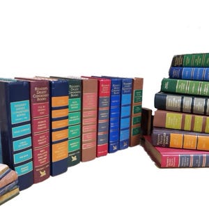 May include: A collection of vintage Reader's Digest Condensed Books, with a variety of colorful spines and titles. The books are arranged in a bookshelf-like display, with some stacked on top of others.