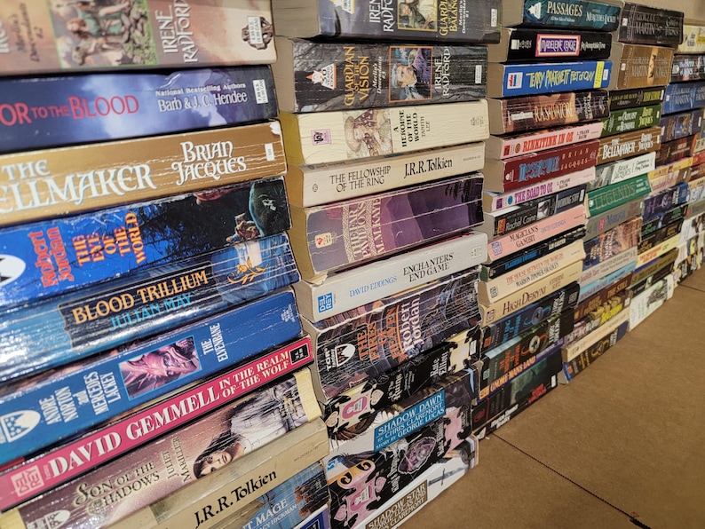 May include: A large stack of paperback books with various titles and authors. The books are arranged vertically, with the spines facing outward. The books are mostly fantasy and science fiction genres.