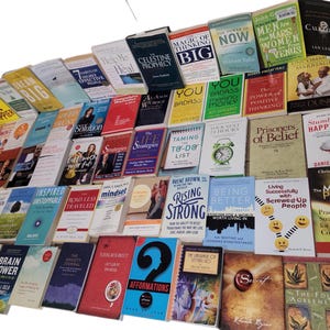 May include: A large collection of self-help and motivational books with titles such as "The Magic of Thinking Big", "You Are a Badass", "The Power of Positive Thinking", "Prisoners of Belief", "The Mediation Process", and "The Four Agreements".