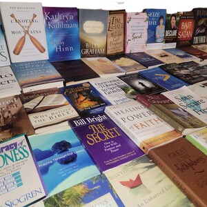May include: A collection of various books with religious themes, including titles such as "Just Like Jesus", "Tortured Christ", "The Healing Power of Faith", and "Seen Secure Free".