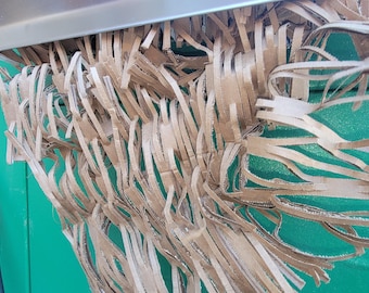 May include: Close-up of a brown paper shredder with shredded paper hanging down in front of a green background.