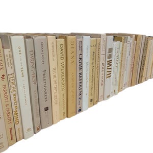 Pu&ograve; includere: Una collezione di libri con copertina rigida con vari titoli e autori. I dorsi sono principalmente color crema, beige e bianco sporco, con titoli come "Love Talk", "Exercise Your Mind" e "Crime Reference". I libri sono disposti in una fila leggermente curva.