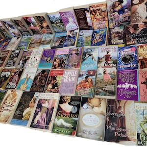 Peut inclure: Une grande collection de romans d'amour en format poche avec diff&eacute;rents titres et auteurs. Les livres sont dispos&eacute;s en rang&eacute;es et pr&eacute;sentent une vari&eacute;t&eacute; de couvertures avec des couleurs et des motifs diff&eacute;rents.