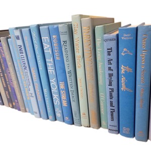 Pu&ograve; includere: Una collezione di libri con copertina rigida in varie tonalit&agrave; di blu, grigio e verde. I dorsi mostrano titoli in lettere dorate. I libri sono disposti ad angolo, creando un'esposizione visivamente accattivante.