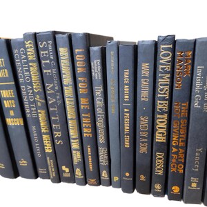 May include: A collection of 20 navy blue hardcover books with gold lettering on the spines. The books are arranged vertically in a row. The titles of the books include "Love Must Be Tough", "The Subtle Art of Not Giving a F*ck", "Self Matters", "Developing the Leader Within You", "Look for Me There", "Seven Promises of a Promise Keeper", "Galileo and the Science Deniers", "Three Days in Moscow", "The Gift of Forgiveness", "Reaching for the Invisible God", "Rekindling the Romance", and more.