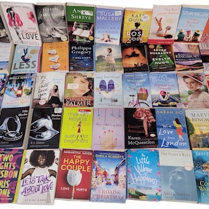 May include: A collection of paperback books with various titles and authors. The books are arranged in rows and columns on a surface. The books are mostly romance novels with colorful covers.