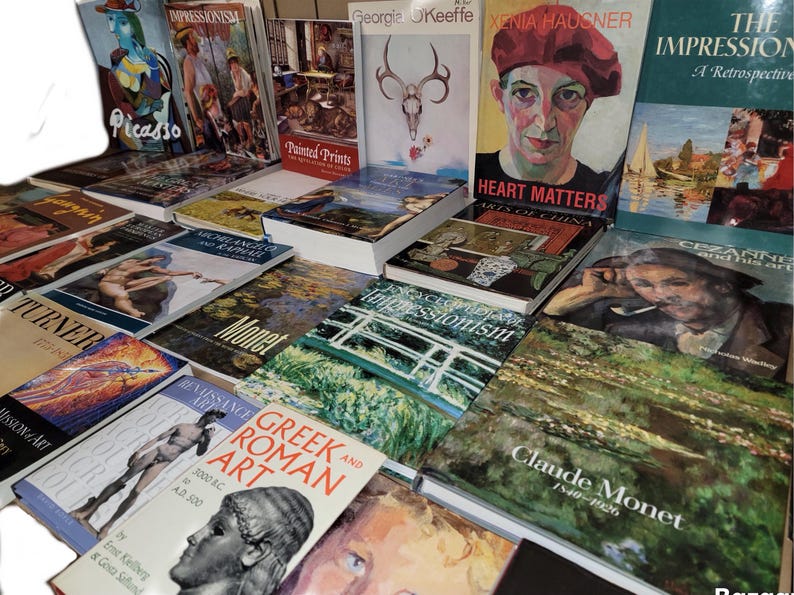 May include: A collection of art books featuring various artists, including Picasso, Turner, Monet, and Claude Monet. The books are arranged in a pile on a table, with the spines facing outward. The titles of the books are visible, as well as the names of the artists.