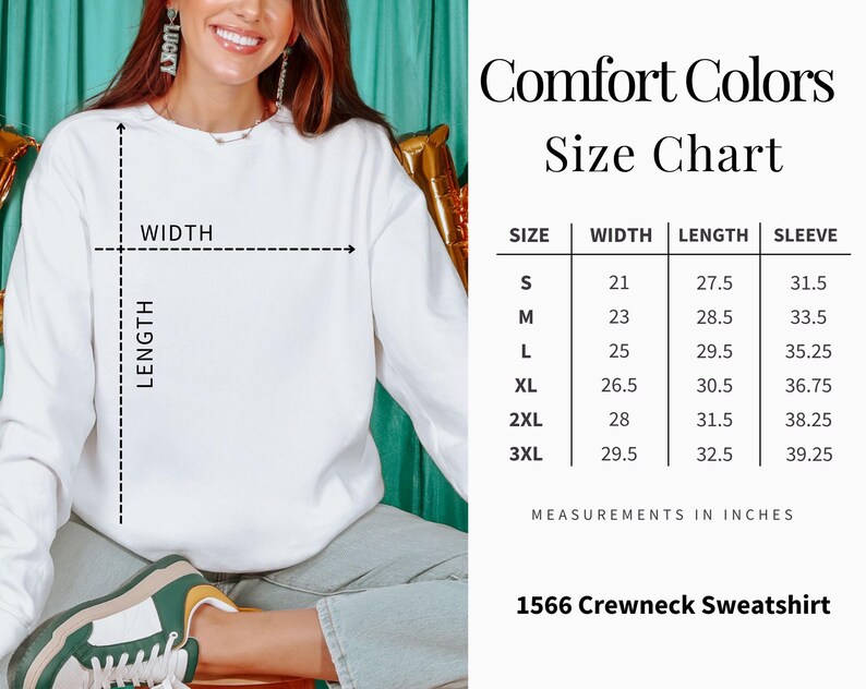 Op de afbeelding: Witte crewneck sweatshirt met een maattabel. De tabel geeft de afmetingen in inches voor breedte, lengte en mouwlengte, vari&euml;rend van maat small tot 3XL. De tekst "Comfort Colors" en "1566 Crewneck Sweatshirt" zijn ook zichtbaar.