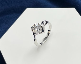 May include: A silver ring with a large, clear, round gemstone set in a twisted band.