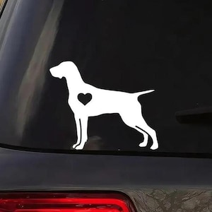 Peut inclure: Un autocollant en vinyle blanc représentant un Braque allemand à poil court avec un cœur sur la poitrine. L'autocollant est sur la lunette arrière d'un SUV noir.