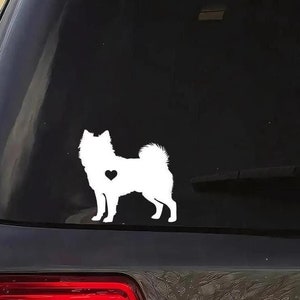 May include: White silhouette of a Finnish Lapphund dog with a small heart on its chest. The silhouette is on a black car window.