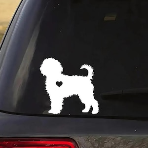 May include: White vinyl decal of a dog silhouette with a heart on the back, on a black car window.