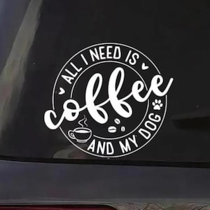 以下が含まれることがあります： ALL I NEED IS coffee AND MY DOGというテキストがブロック体と筆記体の組み合わせでデザインされた、白い円形のビニールステッカー。湯気の立つ小さなコーヒーカップ、2粒のコーヒー豆、肉球のマーク、2つの小さなハートのアイコンが描かれています。