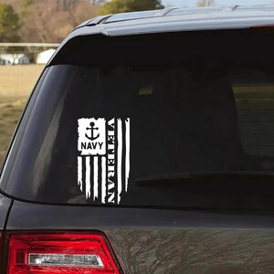 K&ouml;nnte beinhalten: Ein wei&szlig;er Vinyl-Aufkleber mit einem amerikanischen Flaggen-Design und den Worten "Veteran" und "Navy" mit einem Anker-Symbol. Der Aufkleber befindet sich auf der Heckscheibe eines schwarzen Autos.