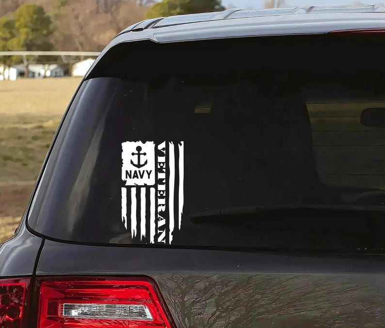 K&ouml;nnte beinhalten: Ein wei&szlig;er Vinyl-Aufkleber mit einem amerikanischen Flaggen-Design und den Worten "Veteran" und "Navy" mit einem Anker-Symbol. Der Aufkleber befindet sich auf der Heckscheibe eines schwarzen Autos.