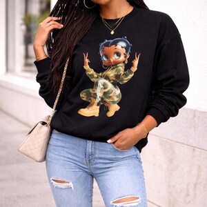 Black crew neck sweatshirt featuring a cartoon Betty Boop character in a camouflage outfit.