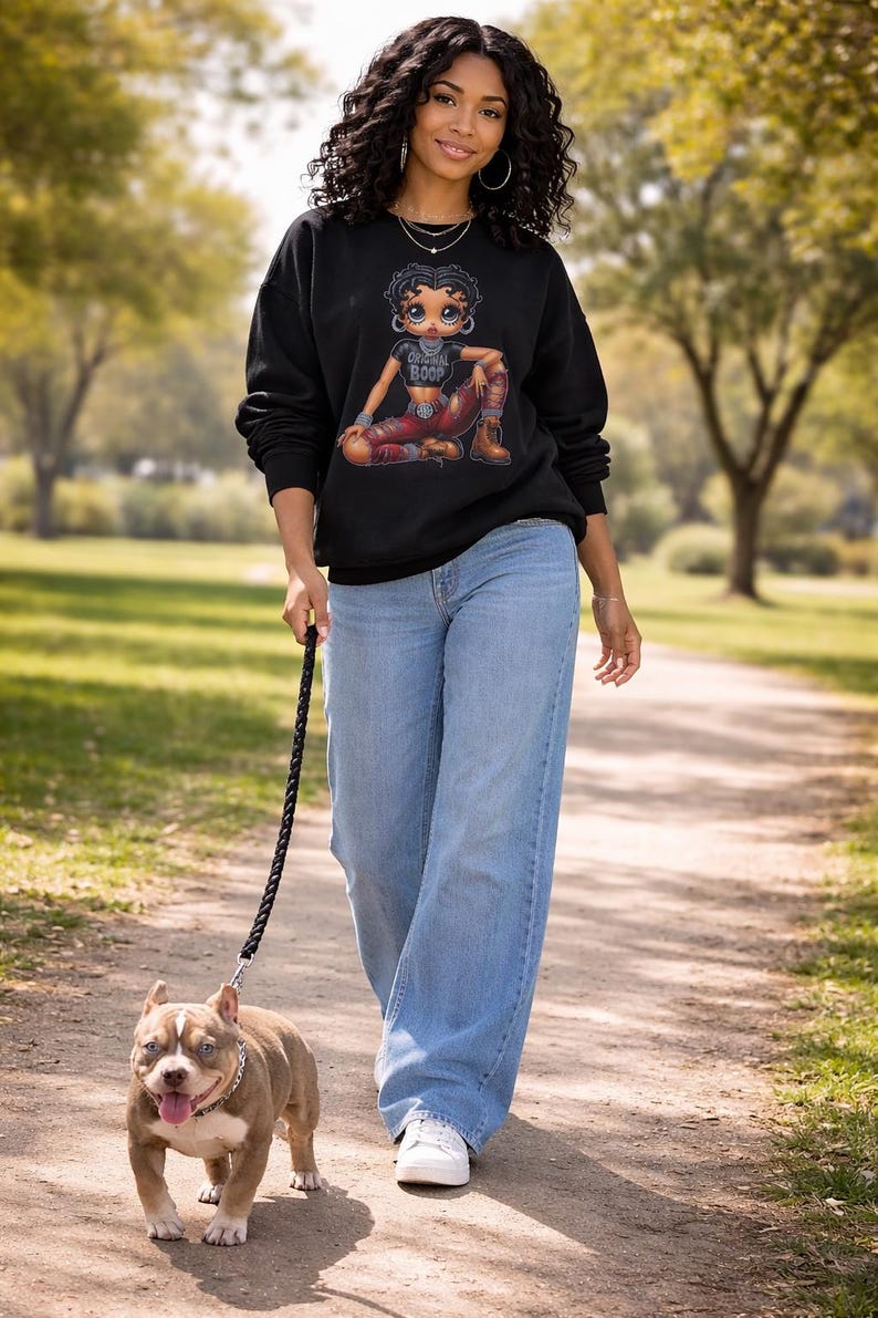 A woman wearing a black sweatshirt with a graphic of a cartoon character and the text "Original Boop". Betty Boop crewneck sweatshirt