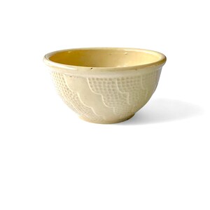 May include: A small, pale yellow ceramic mixing bowl with a textured, wavy design.
