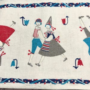 May include: A cream-colored fabric featuring a repeating pattern of stylized figures in red, blue, and gray. The figures wear hats and striped clothing, interspersed with small red and blue tulip-like floral motifs. A decorative border frames the top and bottom.