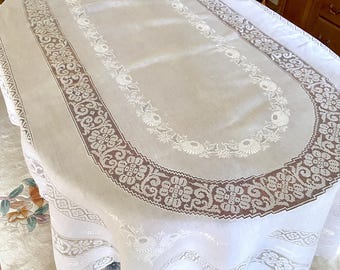 May include: White oval tablecloth with a delicate lace border and a floral design in the center. The lace border features a repeating pattern of flowers and leaves.