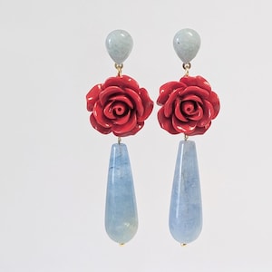 May include: A pair of dangle earrings featuring a red rose flower charm and a light blue teardrop-shaped stone.