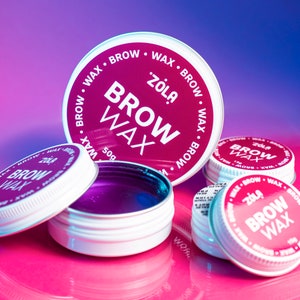 May include: Four small round containers of purple brow wax with a pink and white label that reads "Zola Brow Wax".