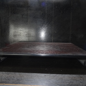 May include: A dark wood display stand with a rectangular top and scrolled ends. The stand has a dark finish and is designed to elevate objects. The stand is approximately 12 inches long and 8 inches wide.