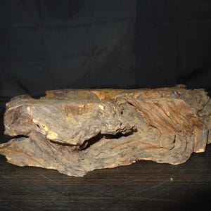 Peut inclure: Un morceau de bois flotté irrégulier et vieilli, mettant en valeur une esthétique naturelle et organique. Le bois présente une gamme de teintes marron et beige, avec un grain et une texture visibles. Le bois flotté semble être un objet décoratif.