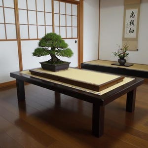 May include: A traditional Japanese interior featuring a low, dark brown wooden table. A bonsai tree in a rectangular pot rests on a light-coloured mat. The room includes sliding doors and a raised platform.