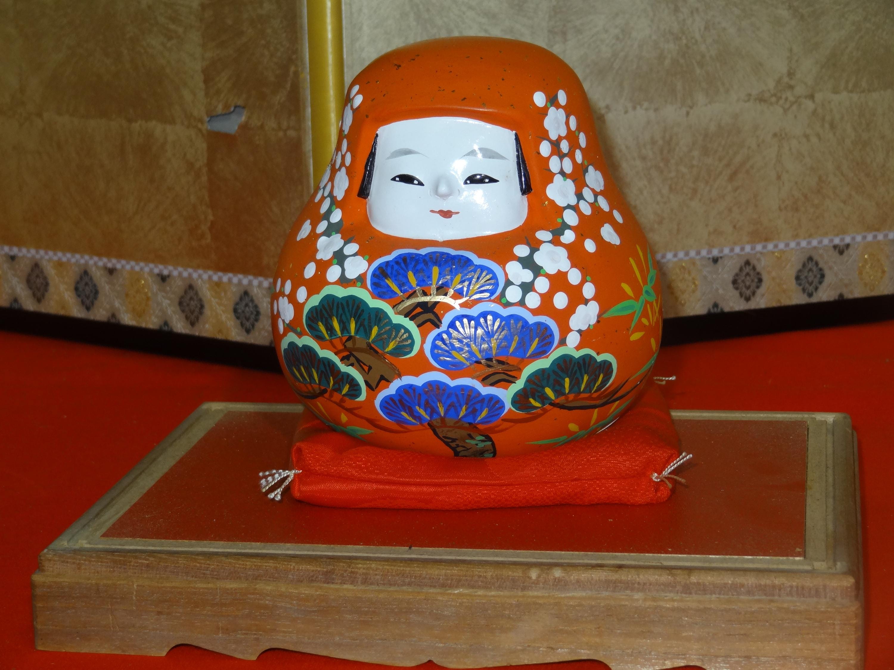 japanese traditional daruma doll hand-painted with pine, plum, bamboo motifs, with cushion and wooden base, lucky ornament, 14cm tall