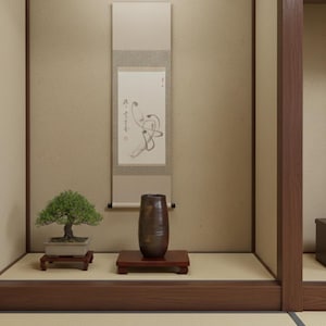 以下が含まれることがあります： 盆栽、濃い茶色の花瓶、書道が施された巻物のある、穏やかな日本のインテリア。 盆栽は小さな木製の台の上にあります。 花瓶も同様の台の上にあります。 巻物は天井から吊り下げられています。