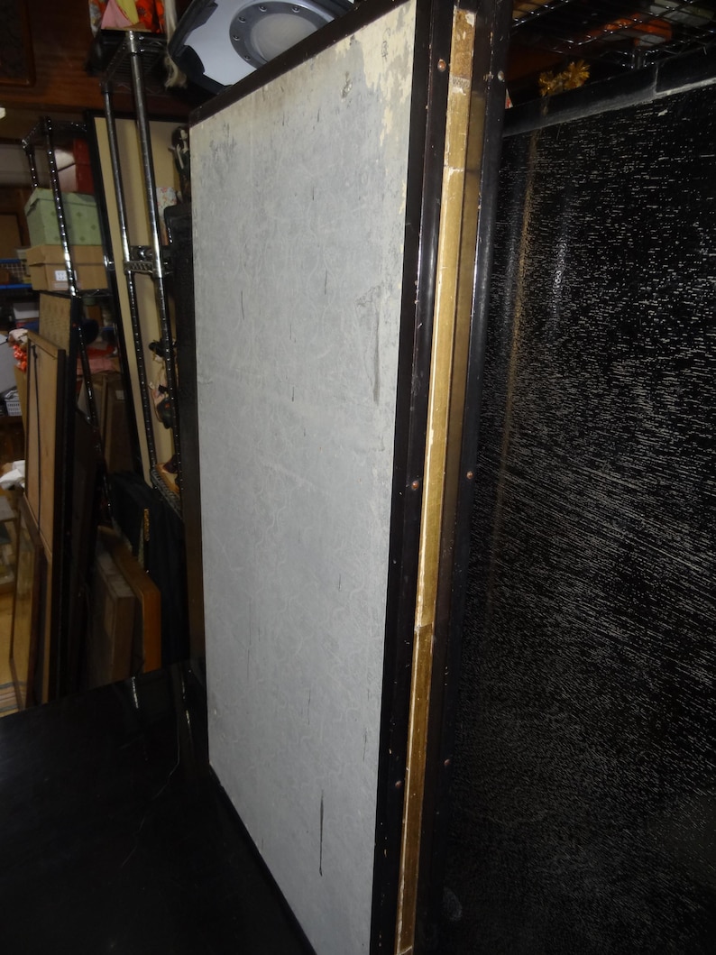 May include: A large, rectangular panel with a light gray surface, framed in dark brown wood with gold accents. The panel appears to be part of a larger piece, possibly a screen or room divider. The background is cluttered.